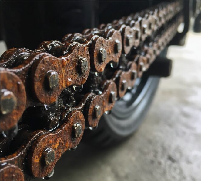 The motorcycle chain was rusty and covered in water droplets.